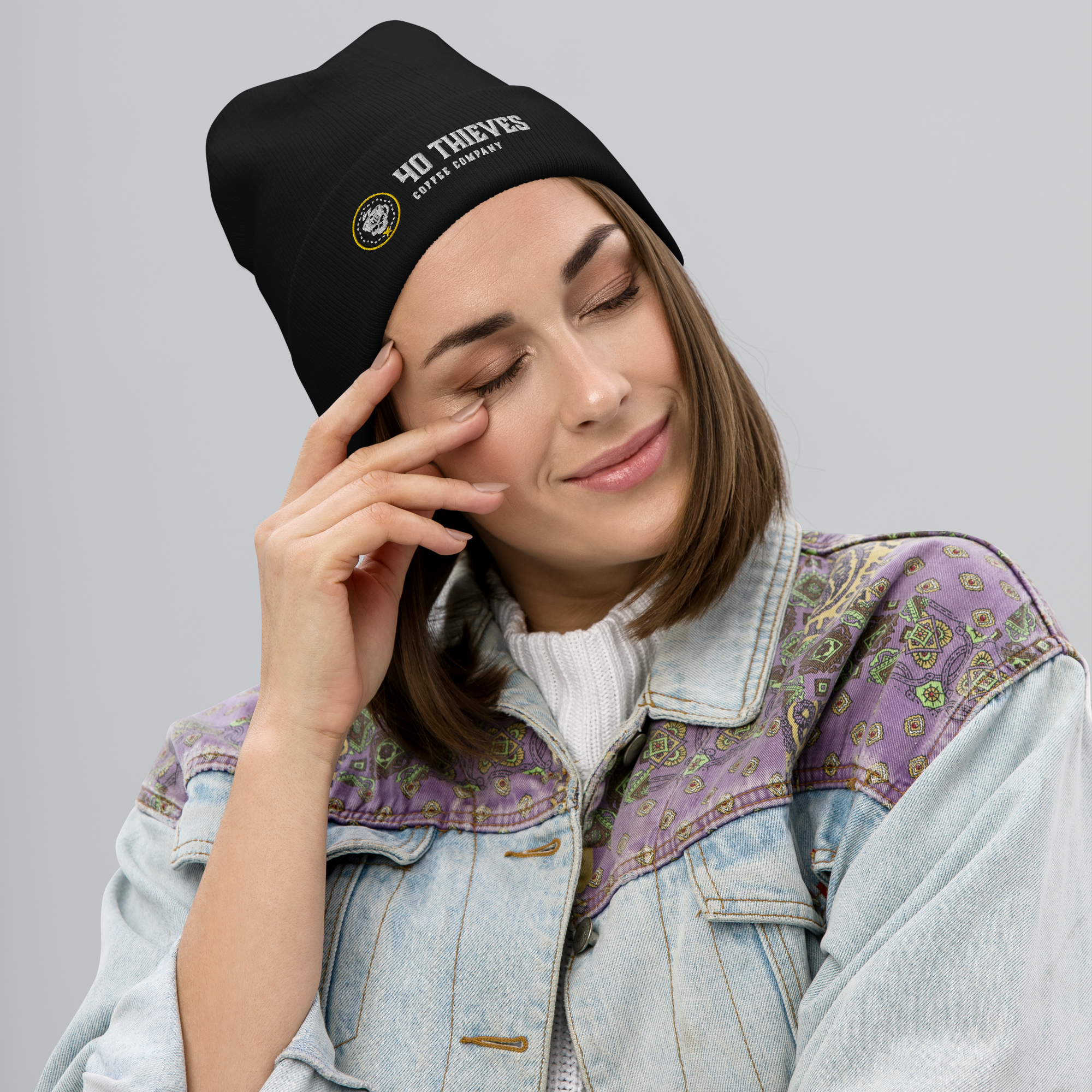 Woman wearing a cozy black Thieves' Beanie with embroidered logo, styled in casual denim jacket.